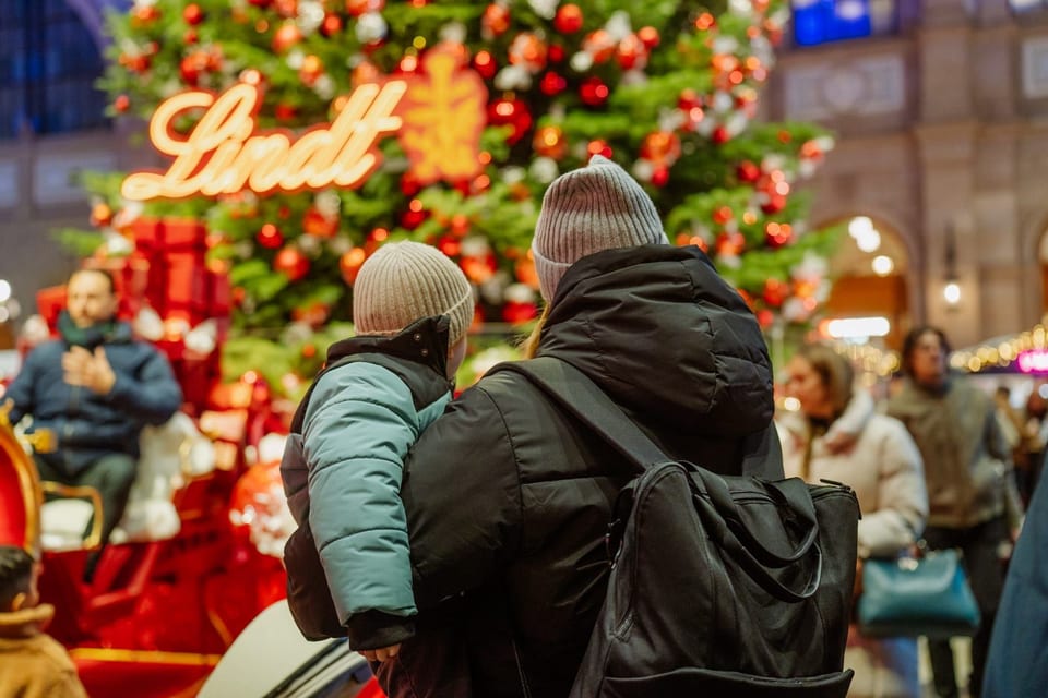 Familie vor dem festlich dekorierten Lindt Weihnachtsbaum